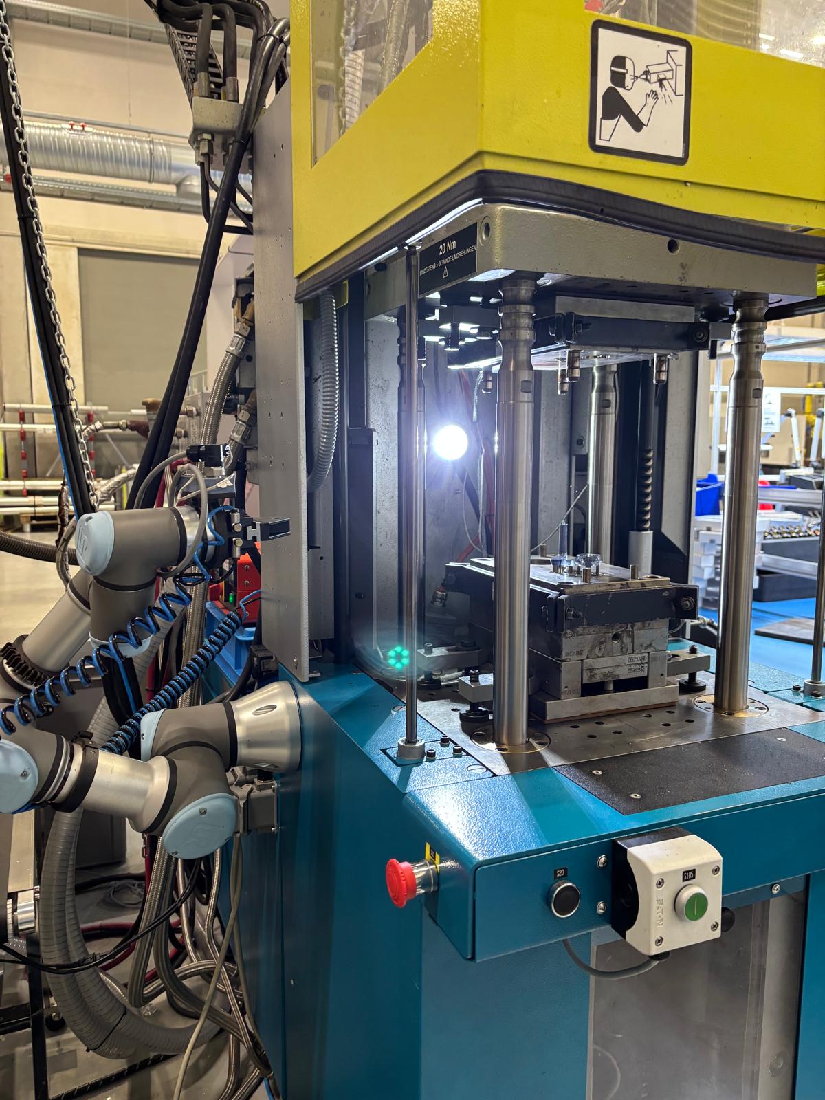 Collaborative robot arm loading an injection moulding machine
